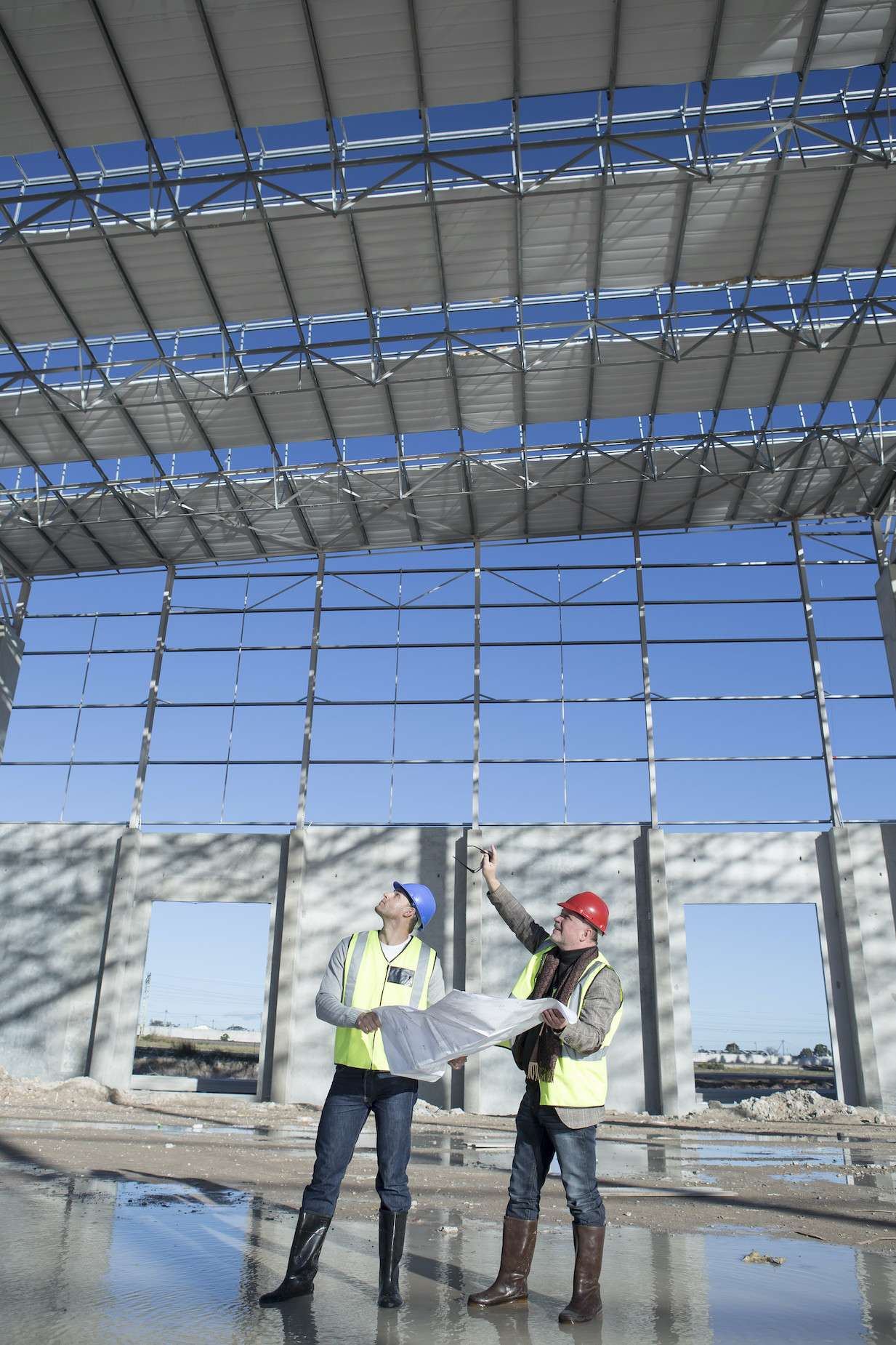 Surveyor and architect looking up at construction frame